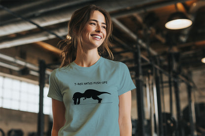 Woman wearing a light blue-Green t-shirt with a dinosaur T-rex graphic and the text T-Rex Hates Push-Ups