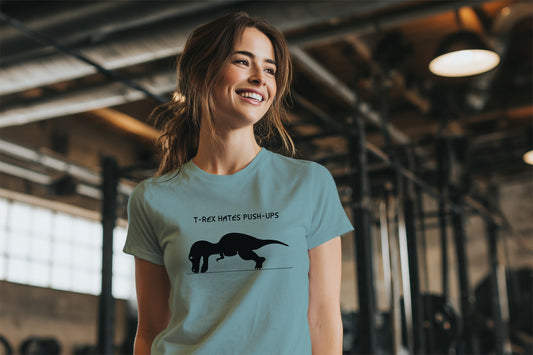Woman wearing a light blue-Green t-shirt with a dinosaur T-rex graphic and the text T-Rex Hates Push-Ups