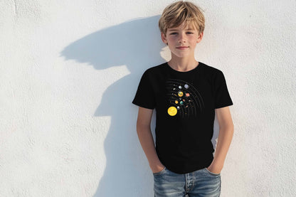 A boy wearing a black short-sleeve tee with a graphic of the solar system on it, standing against a white wall.